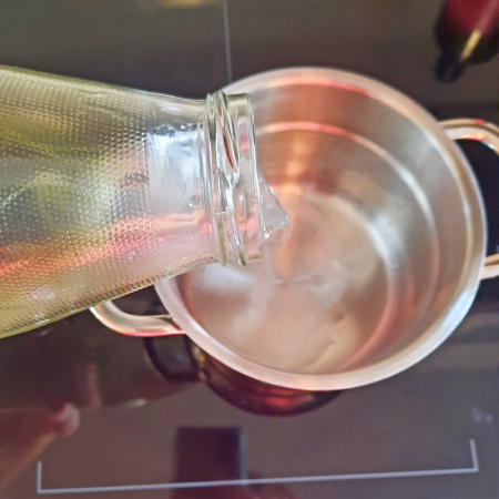 Zinnkraut in Wasser wird von der Glasflasche in einen Topf geleert