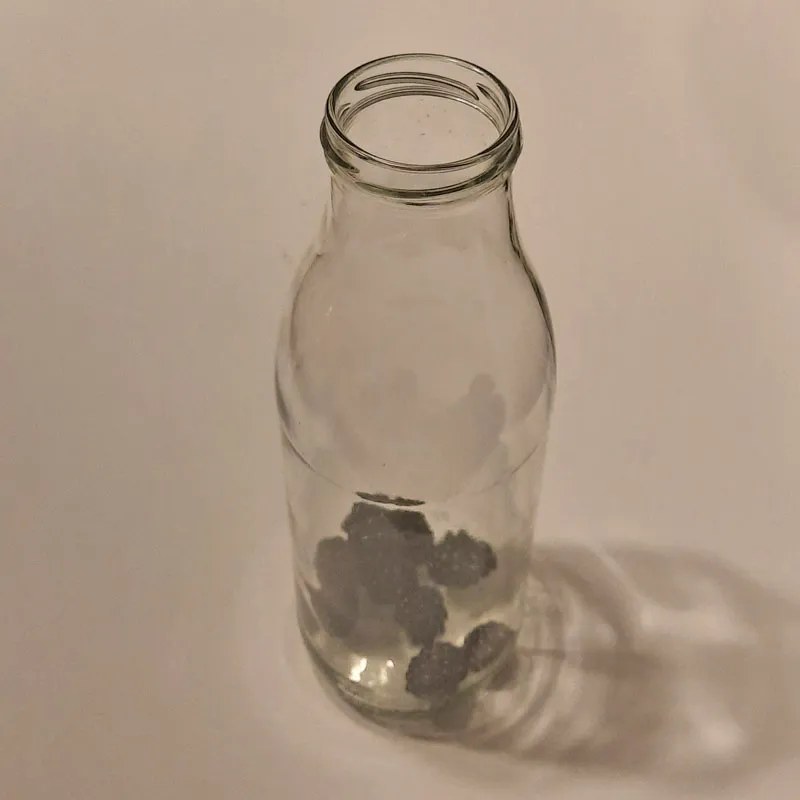 Hausmittel bei Schlafproblemen wird hergestellt: Am Foto sieht man eine Glasflasche mit 10 Brombeeren gefüllt.